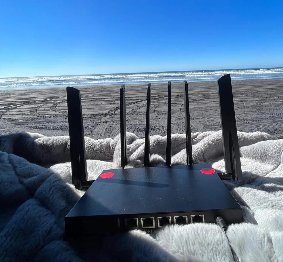 The Cat 20 router standing on a blanket in the open back of a vehicle, parked facing the ocean on a beach.